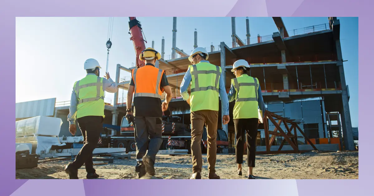 Group of construction professionals in safety gear walking through an active job site